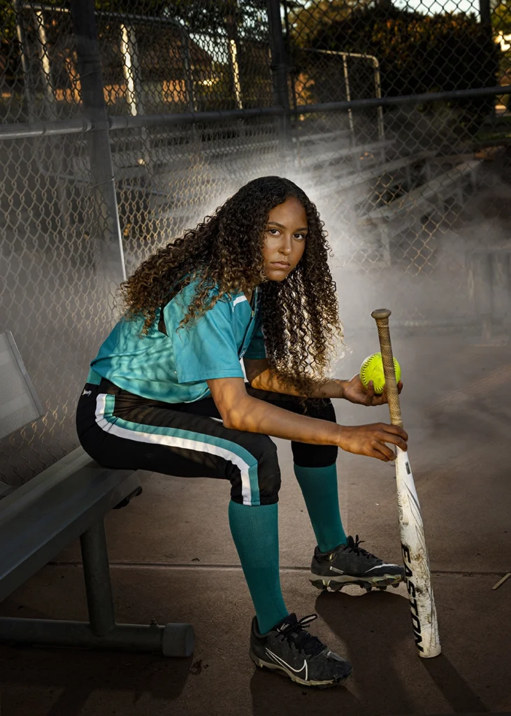 Sports Rock Media Photography: A young girl holding a baseball and bat while sitting down.